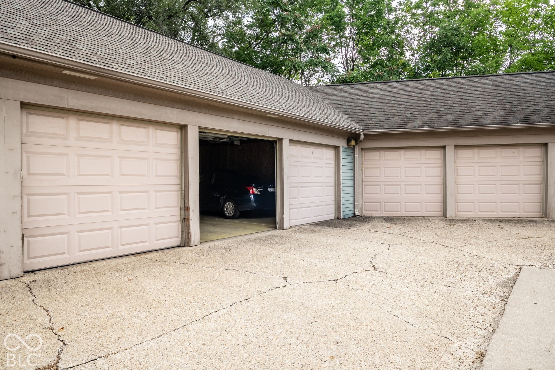 Attached multi-stall garage with panel-style doors and shingle roofing