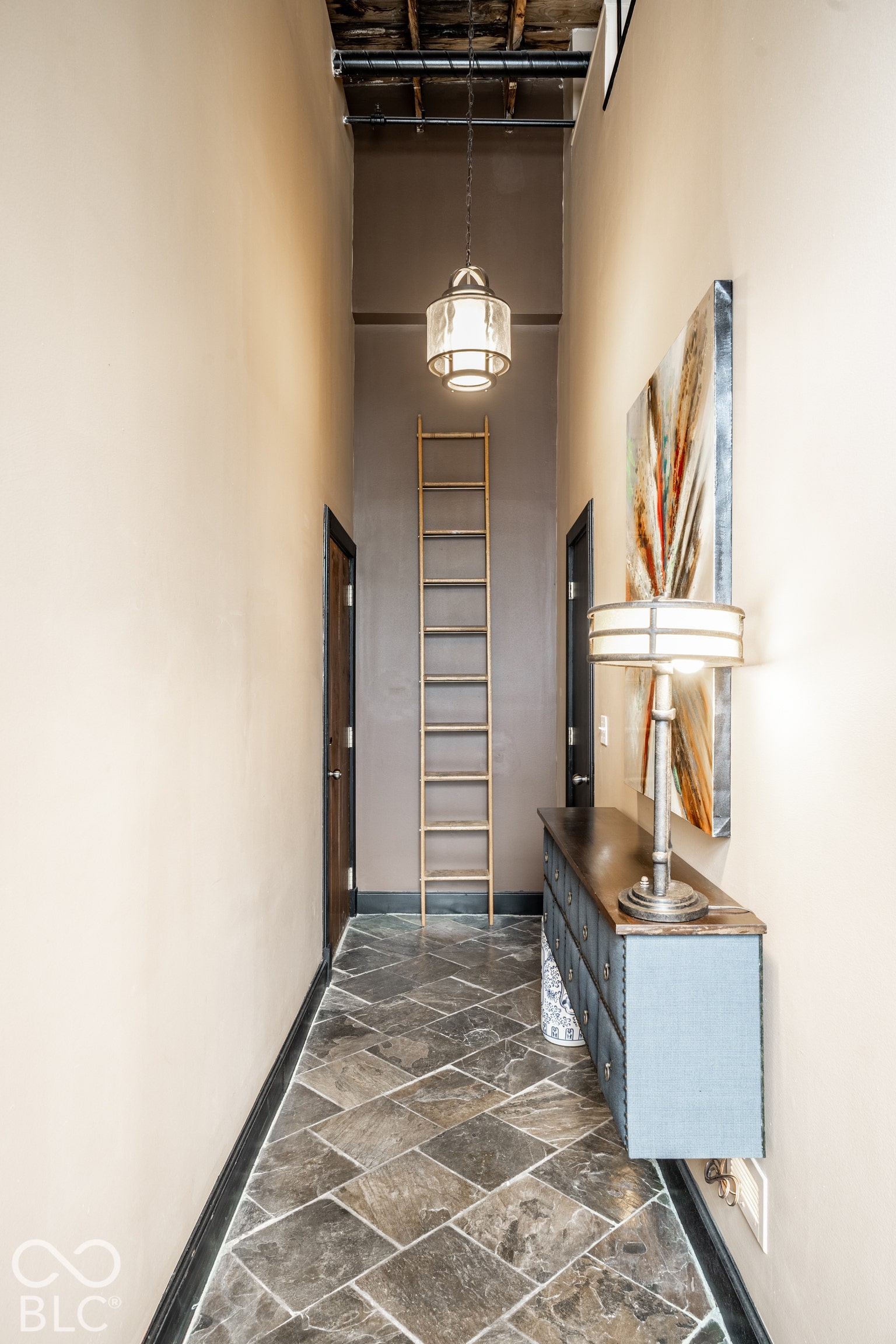 Patterned stone tile flooring, high ceilings with exposed ductwork, and a decorative ladder feature