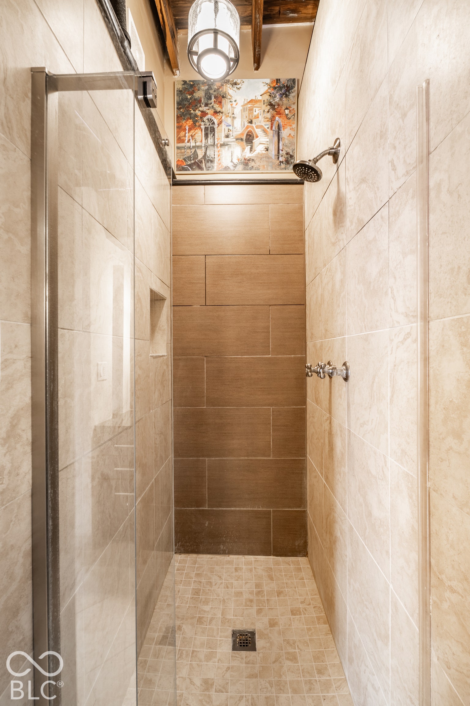 Tile-enclosed shower with a glass panel, recessed niche, and a fixed showerhead