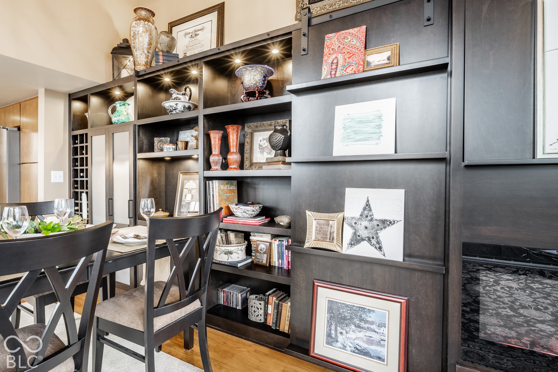 Custom built-in shelving with integrated lighting, a dedicated wine rack, and a built-in fireplace feature