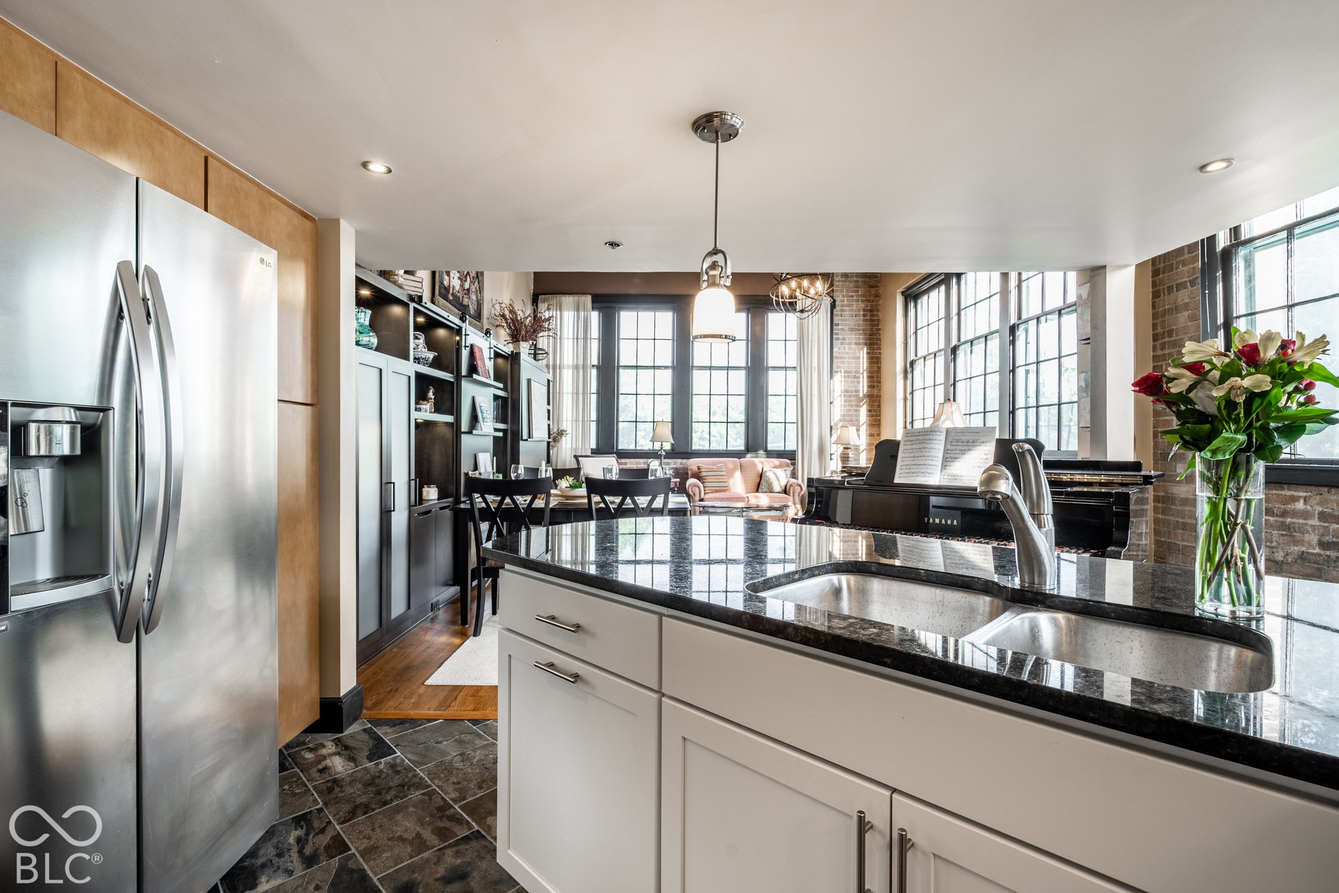 Kitchen island featuring a dual basin sink and dark granite-style countertop