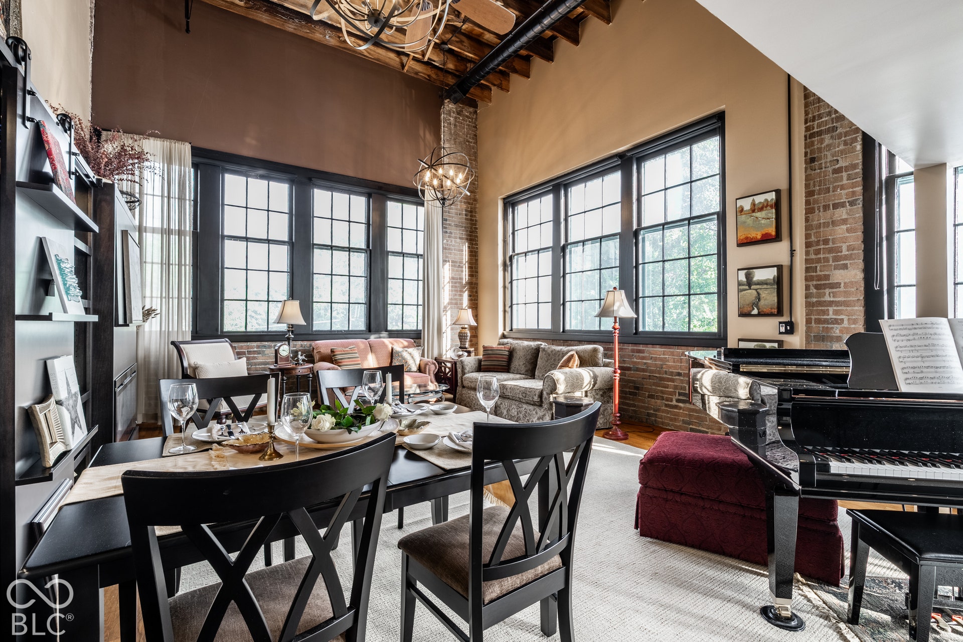 Exposed brick walls, expansive grid-pattern windows, and a black dining set with X-back chairs