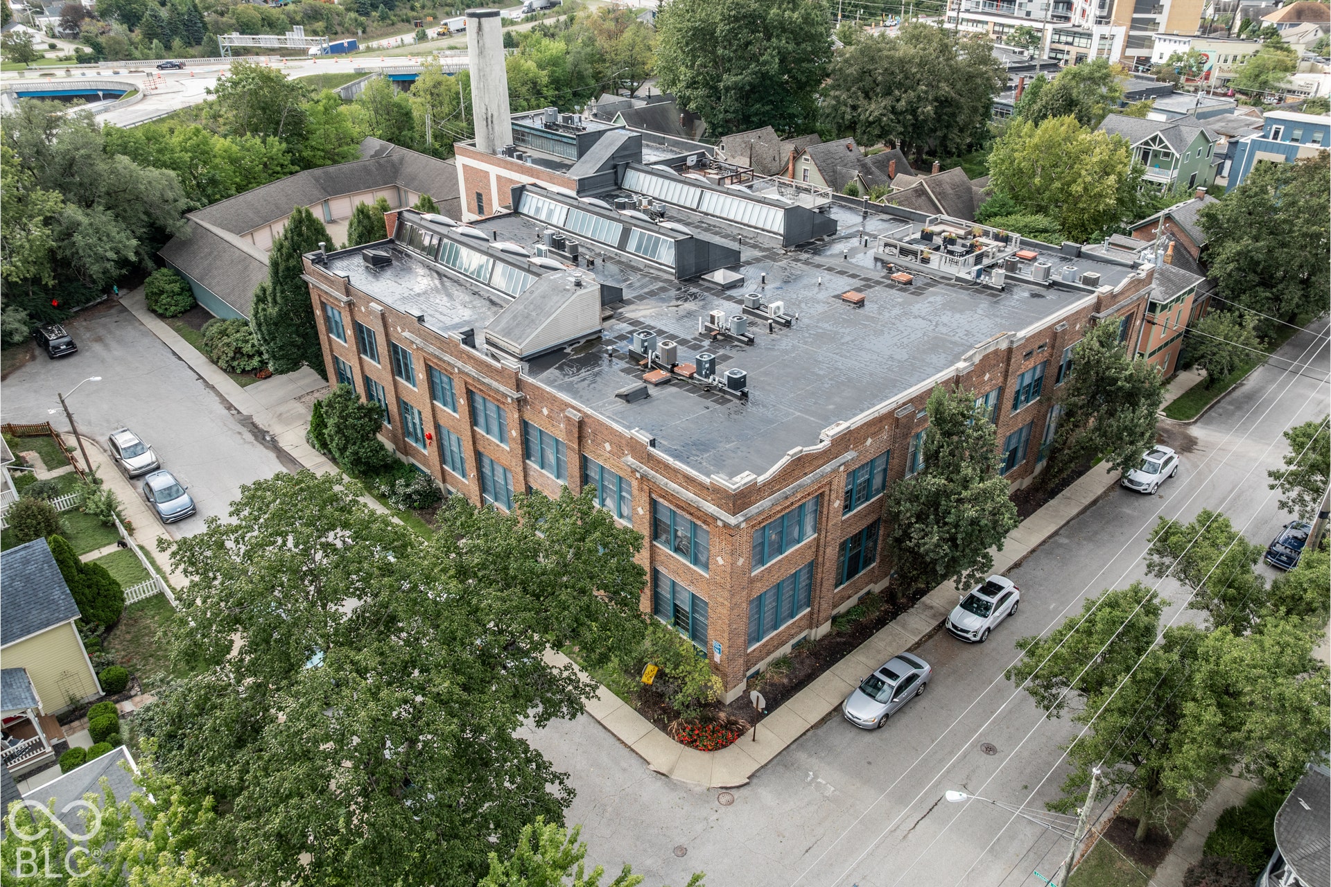 Brick exterior building with multiple windows, flat roofline, and visible rooftop units