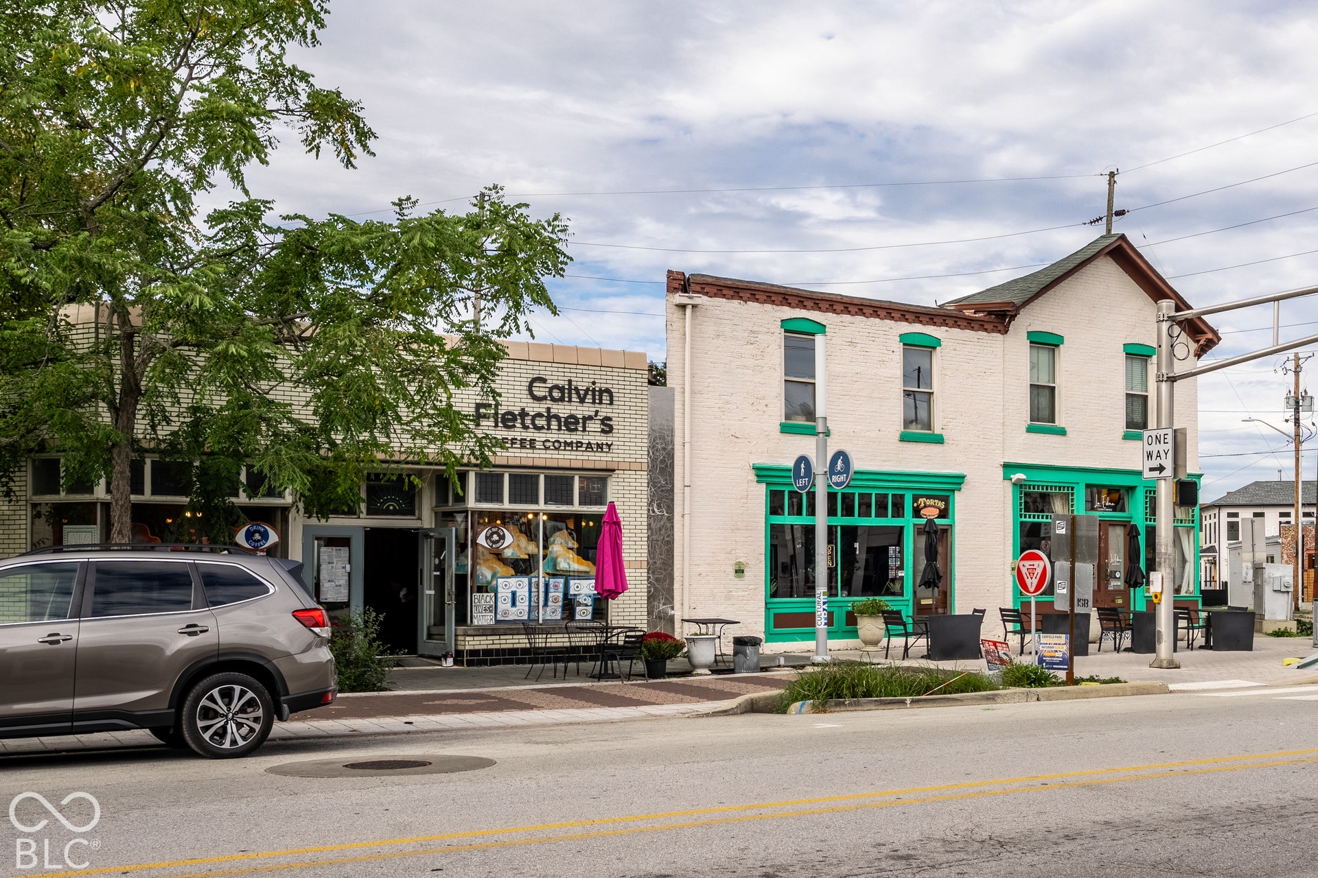 Brick facade with a storefront entry, large display windows, and outdoor seating