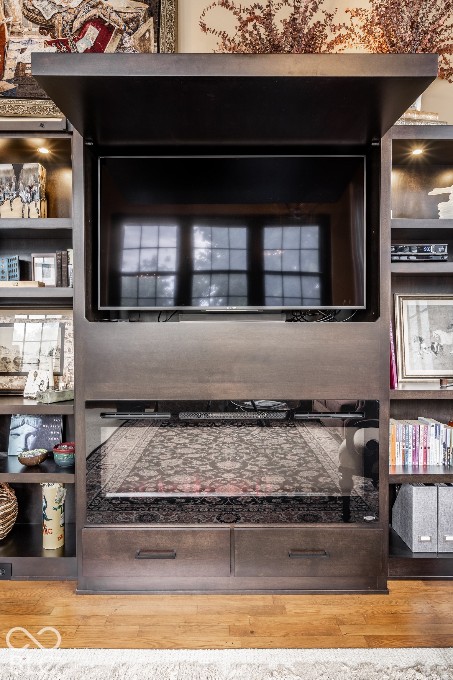 Built-in entertainment center featuring a concealed television, integrated shelving with recessed lighting, and two storage drawers with dark hardware