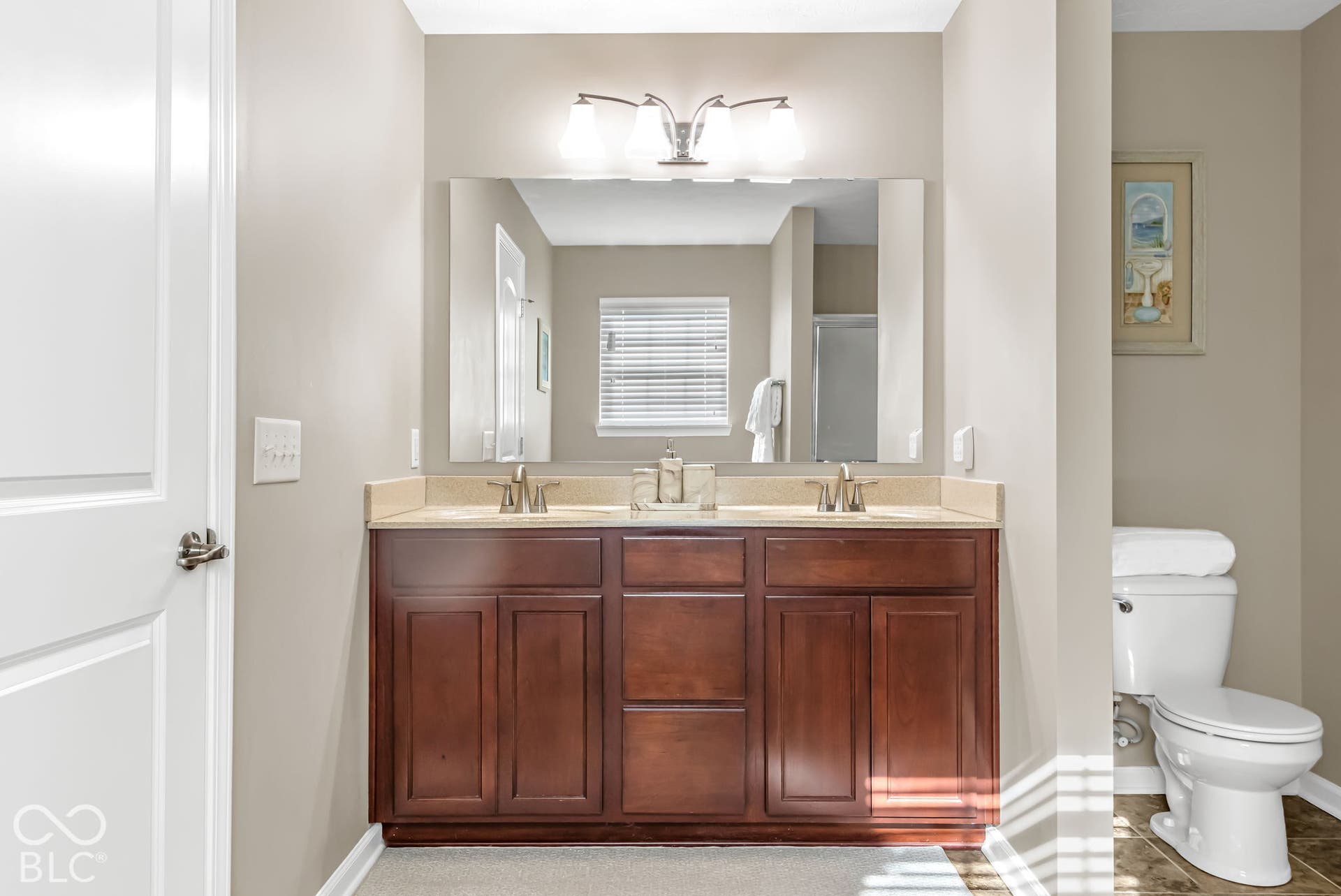 Double vanity with wood-finish cabinetry, dual sinks, and an overhead light fixture