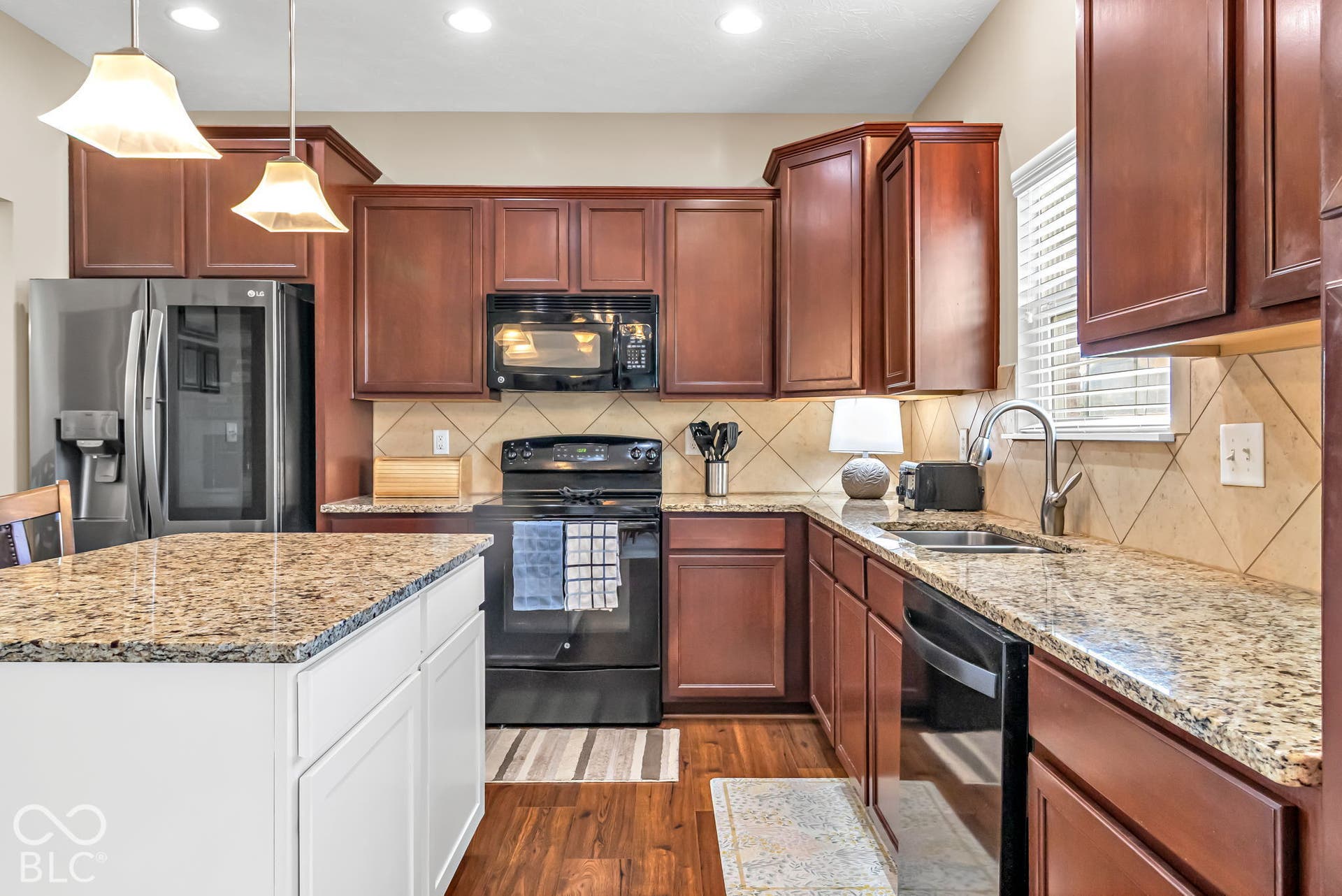 Kitchen featuring wood-finish flooring, dark wood cabinetry, and granite countertops