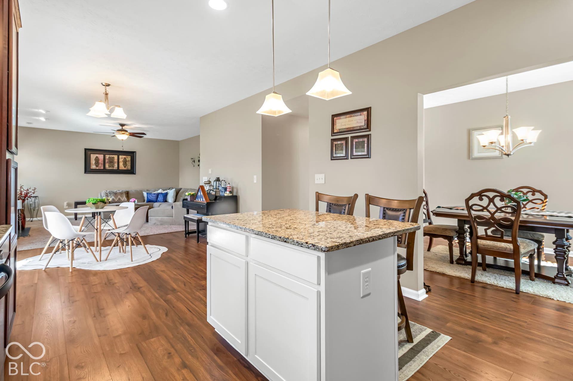 Kitchen island with a granite-style countertop, white cabinetry, and pendant lighting
