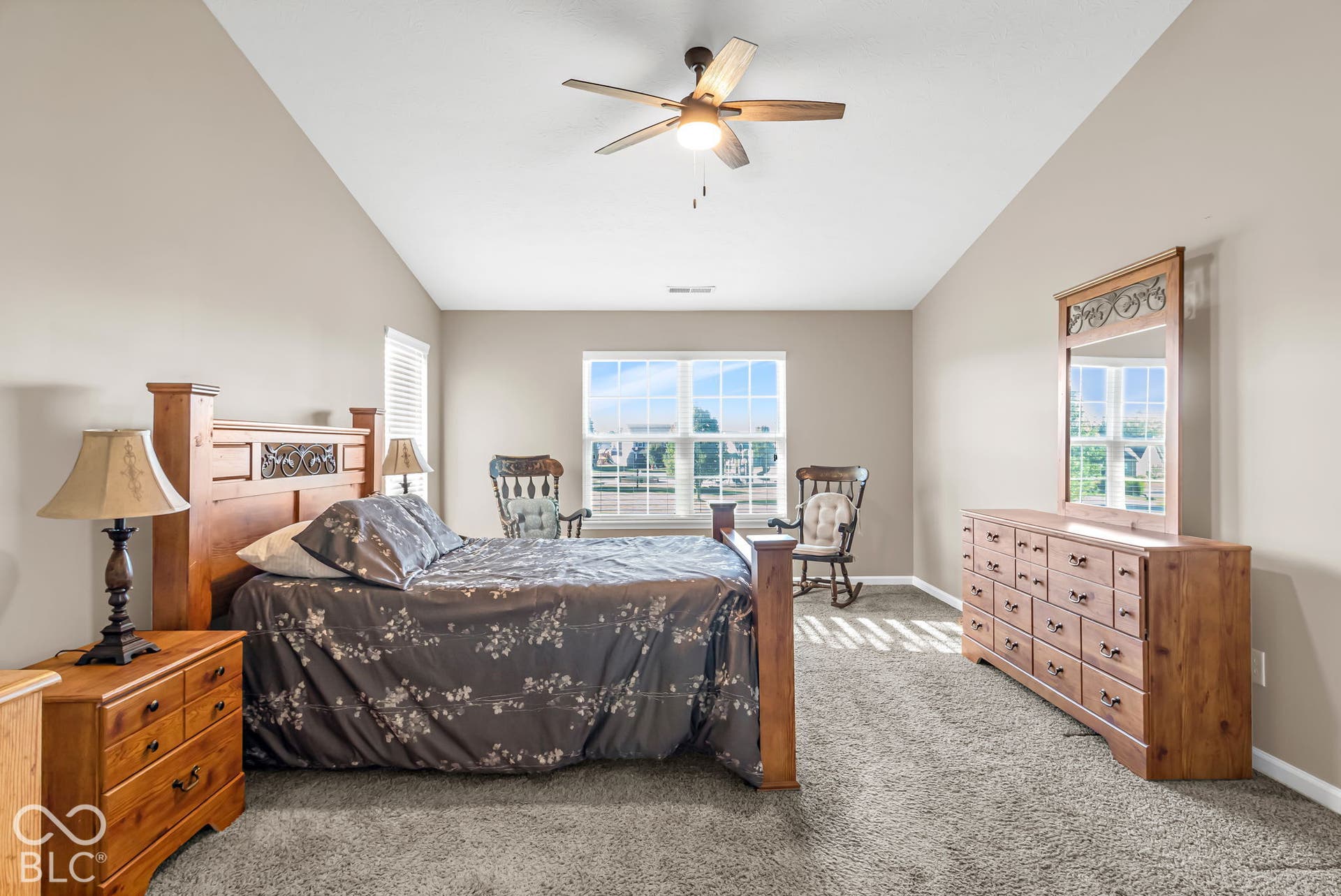 Vaulted ceiling with an attached ceiling fan, dual windows, and wall-to-wall carpeting