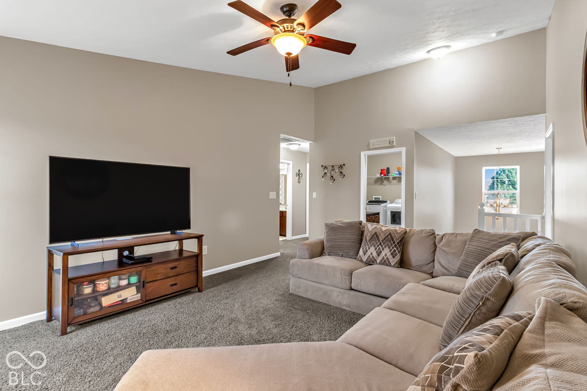 Vaulted ceiling with an attached ceiling fan, neutral wall paint, and gray carpet flooring