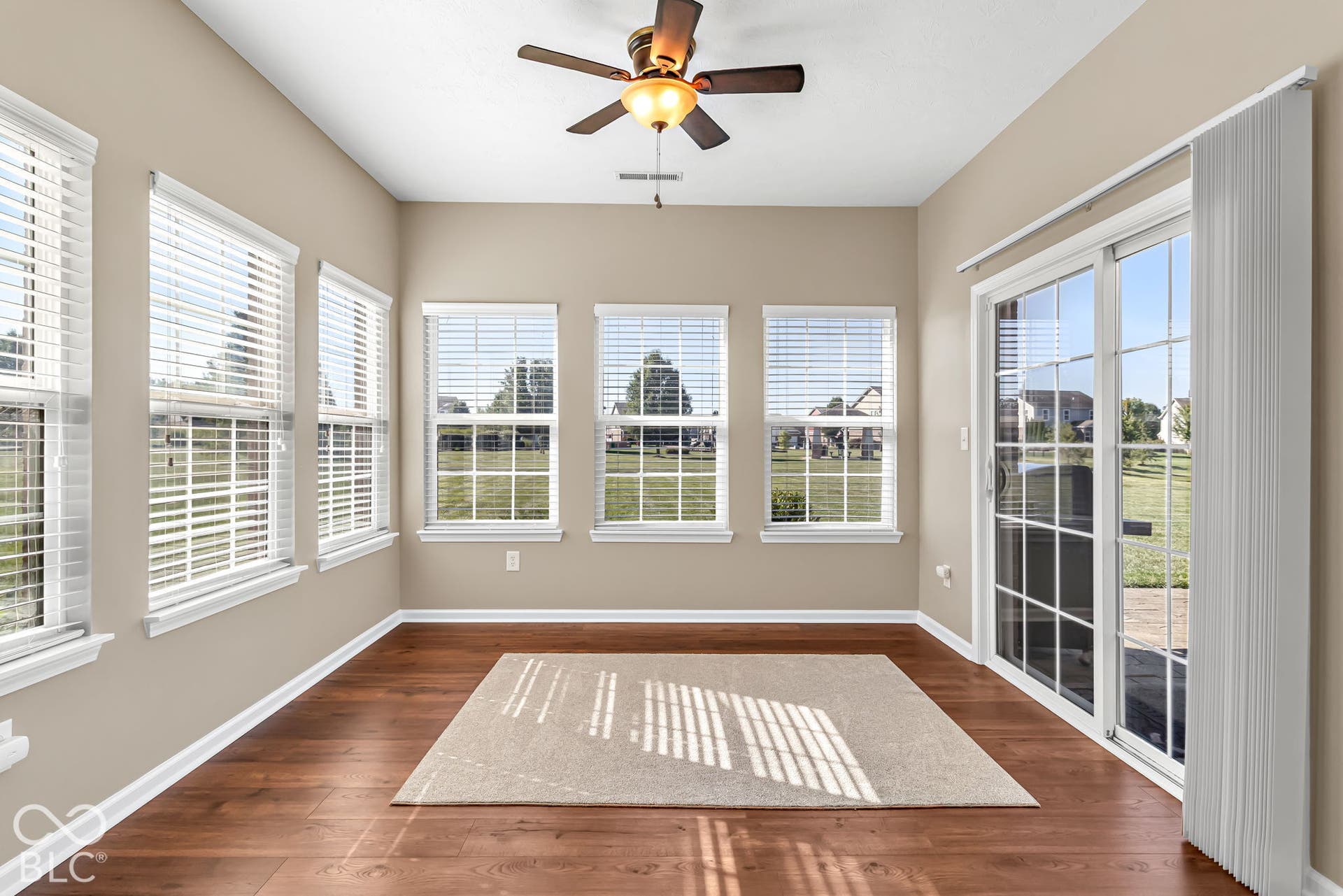 Vaulted ceiling with a ceiling fan, wood-finish flooring, multiple windows with blinds, and a glass sliding door