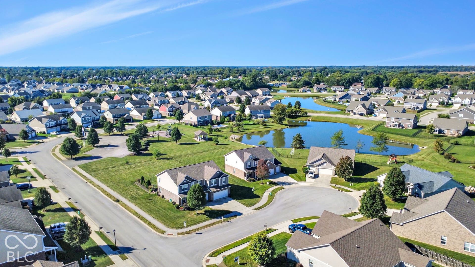 Neighborhood setting featuring residential properties, mature trees, and a prominent water feature
