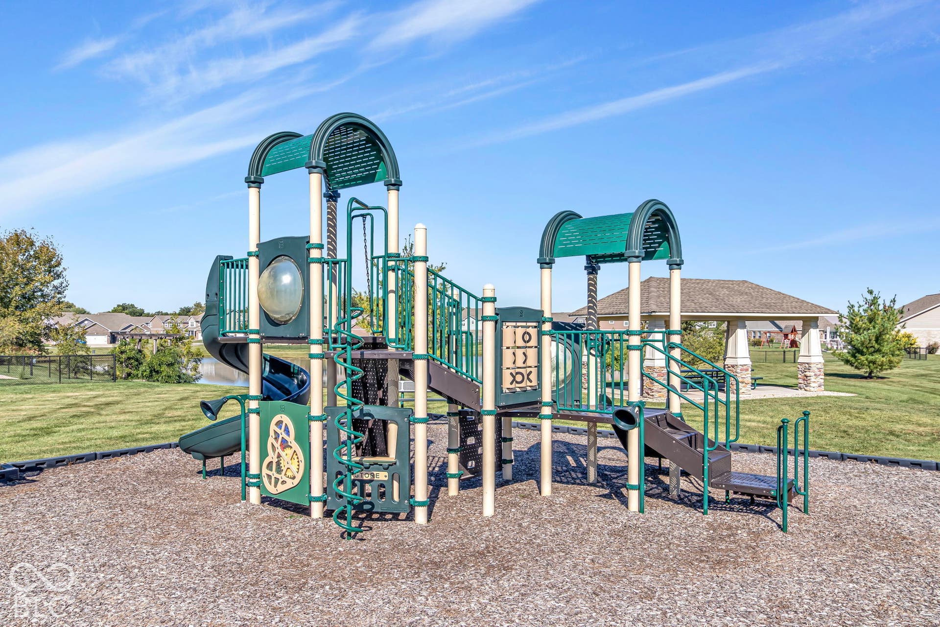 Playground area featuring multiple slides, climbing structures, a tic-tac-toe panel, and a covered pavilion