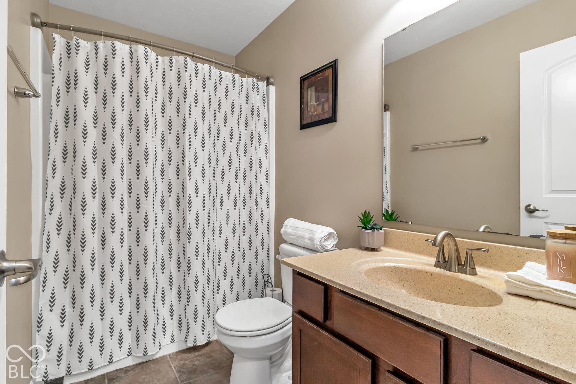 Bathroom featuring a vanity with an integrated sink, a brushed nickel faucet, a frameless mirror, and a curved shower rod