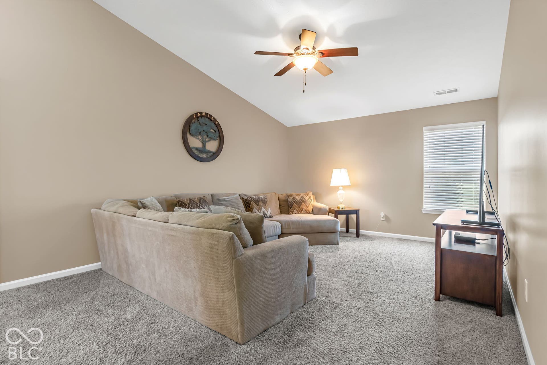 Vaulted ceiling with a ceiling fan, neutral wall tones, and carpeted flooring