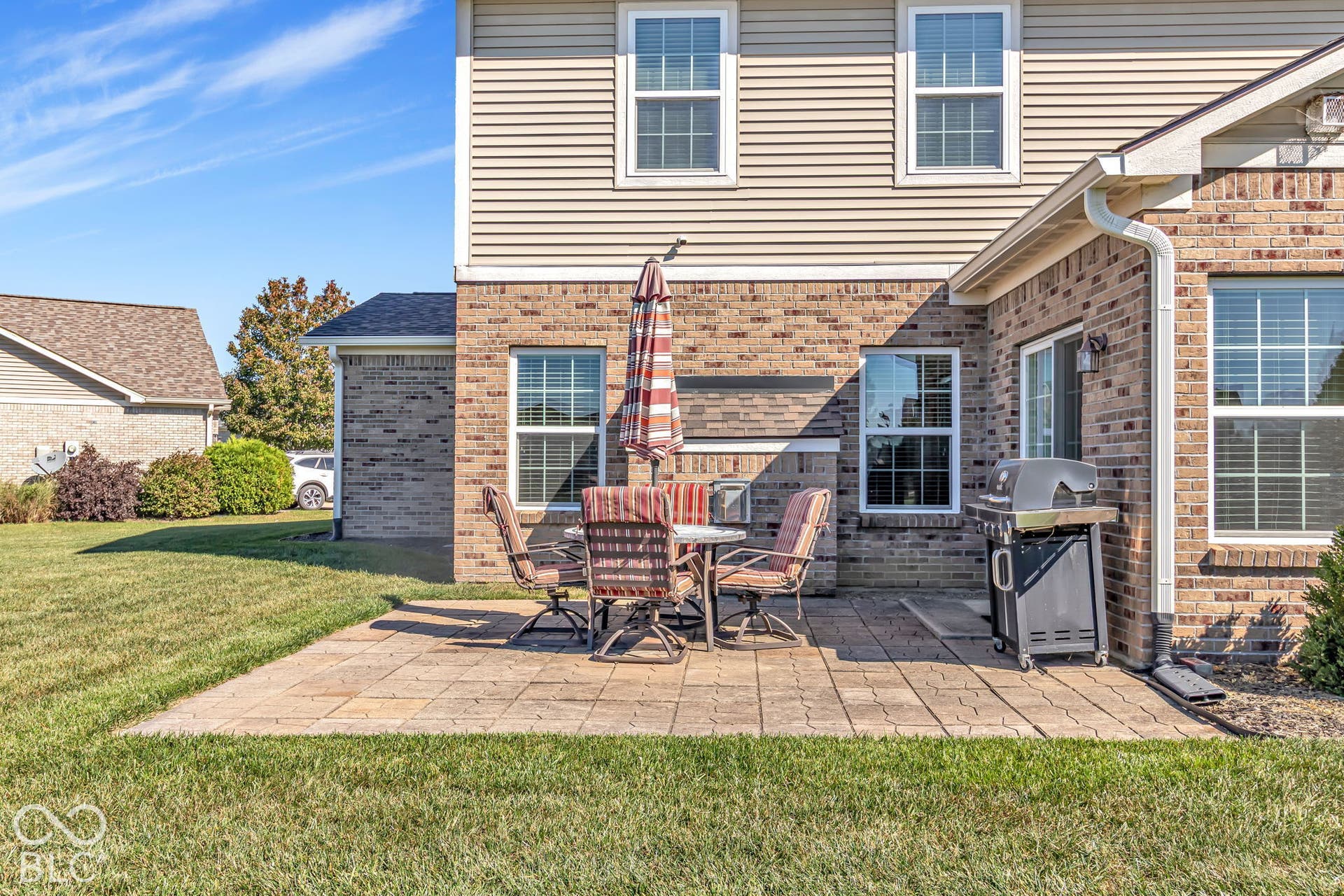 Patio with paver flooring, brick and siding exterior, multiple windows, and a sliding glass door