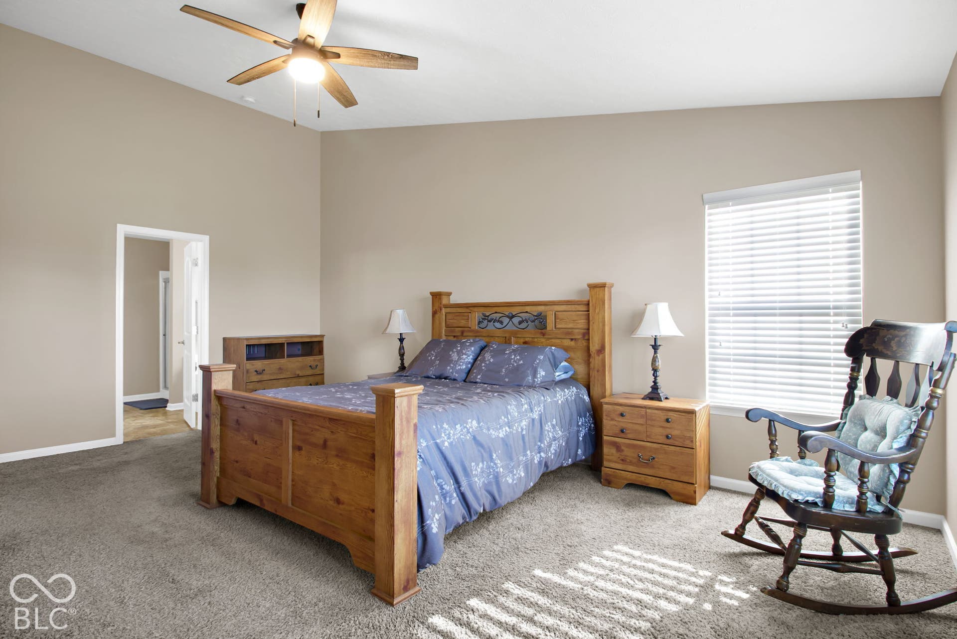 Carpeted flooring with a ceiling fan light fixture, light-colored walls, and a window with blinds