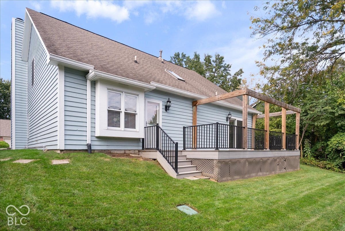 Exterior siding, rear deck with wooden pergola, black metal railings, and skylight