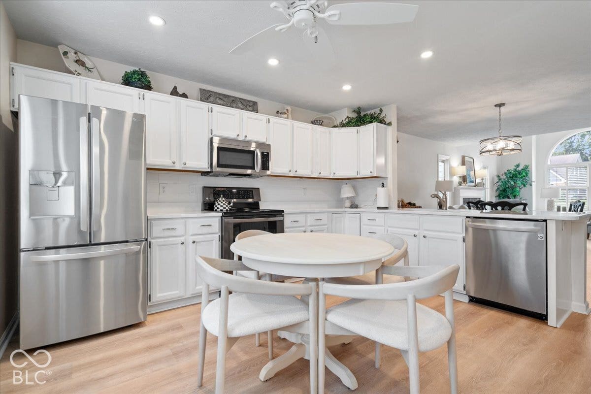 Kitchen featuring white cabinetry, stainless steel appliances, light-toned wood-finish flooring, recessed lighting, and a ceiling fan