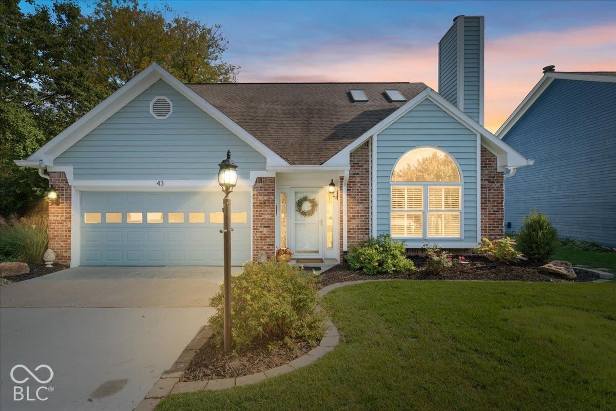 Exterior featuring horizontal lap siding, brick masonry accents, a decorative arched window, skylights, and a chimney stack