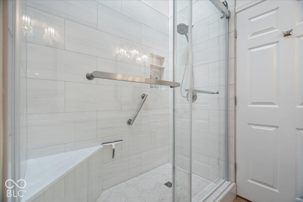 Recently remodeled!! Walk-in shower featuring large-format wall tile, a built-in bench, a recessed niche, a glass enclosure, and a handheld shower fixture