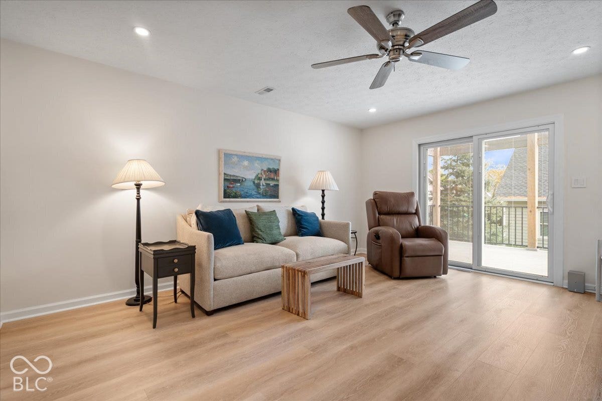 Primary Bedroom currently used as family room. Featuring light wood-finish flooring, recessed lighting, ceiling fan, and sliding glass doors to large Trex Deck.