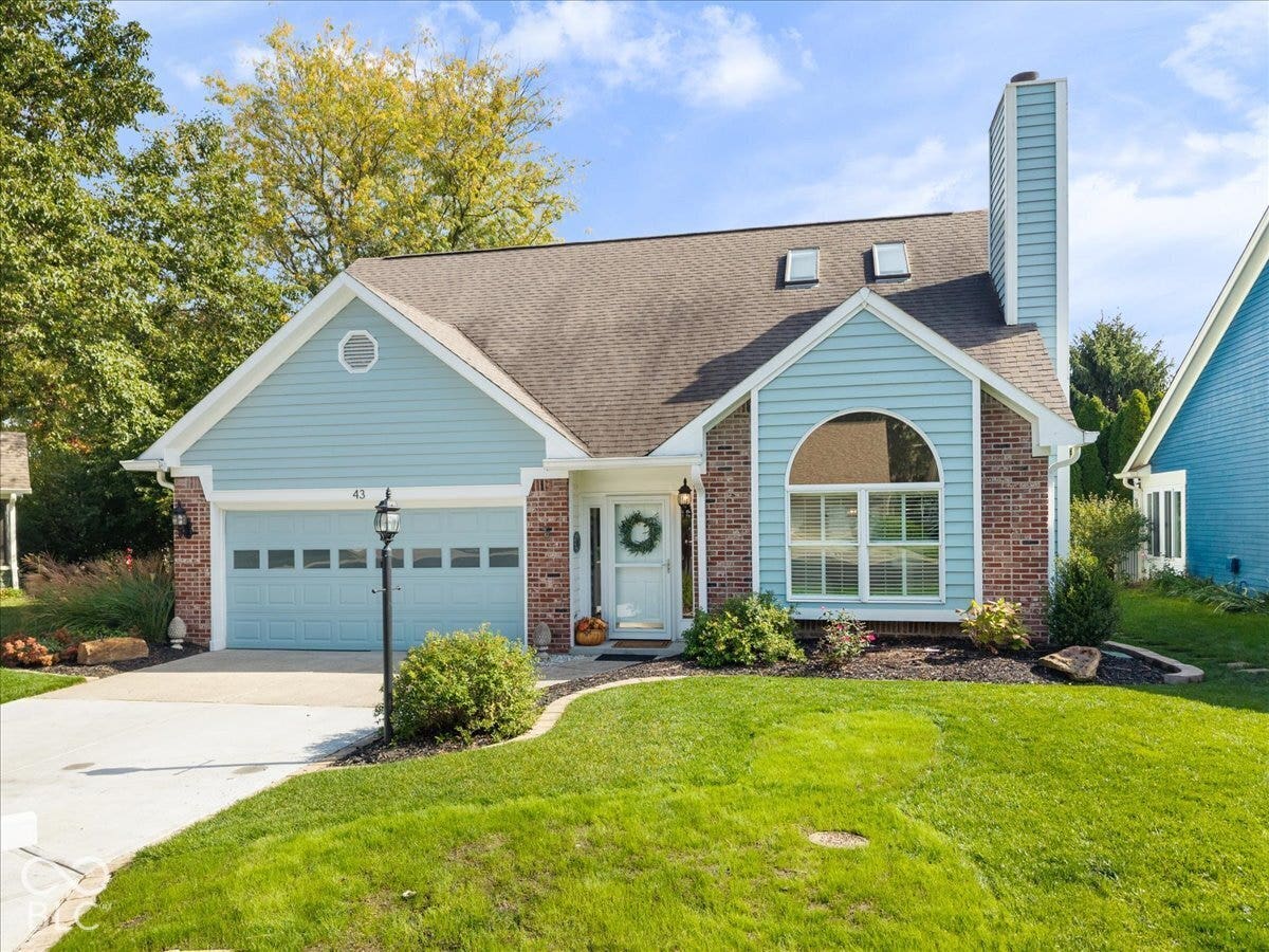 Exterior featuring a blend of brick and light blue horizontal siding, arched window, two roof-mounted skylights, and an attached two-car garage