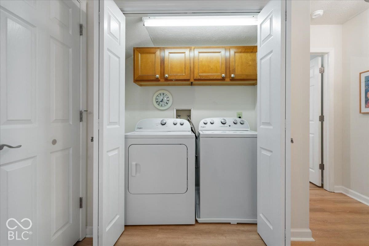 Main level Laundry area featuring bi-fold closet doors, wall-mounted wood-finish cabinetry, and overhead linear lighting