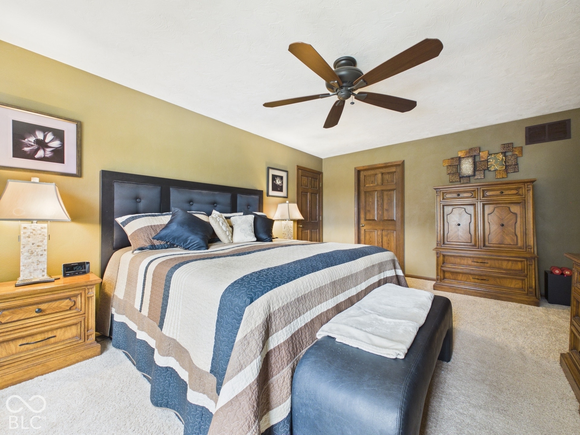 Ceiling fan with wooden blades, two panel wooden doors, and wall-to-wall carpeting
