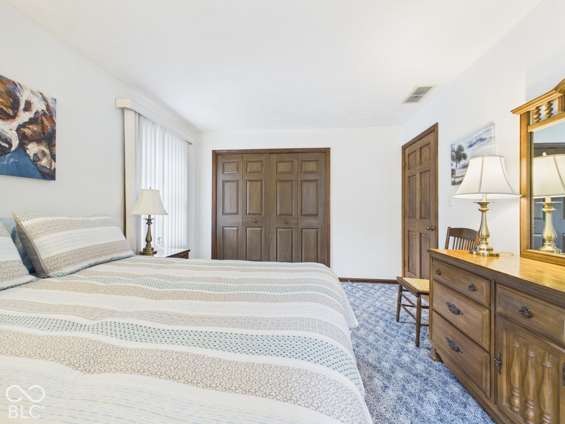 White walls, wood-finish bi-fold closet doors, wood-finish paneled door, and carpeted flooring