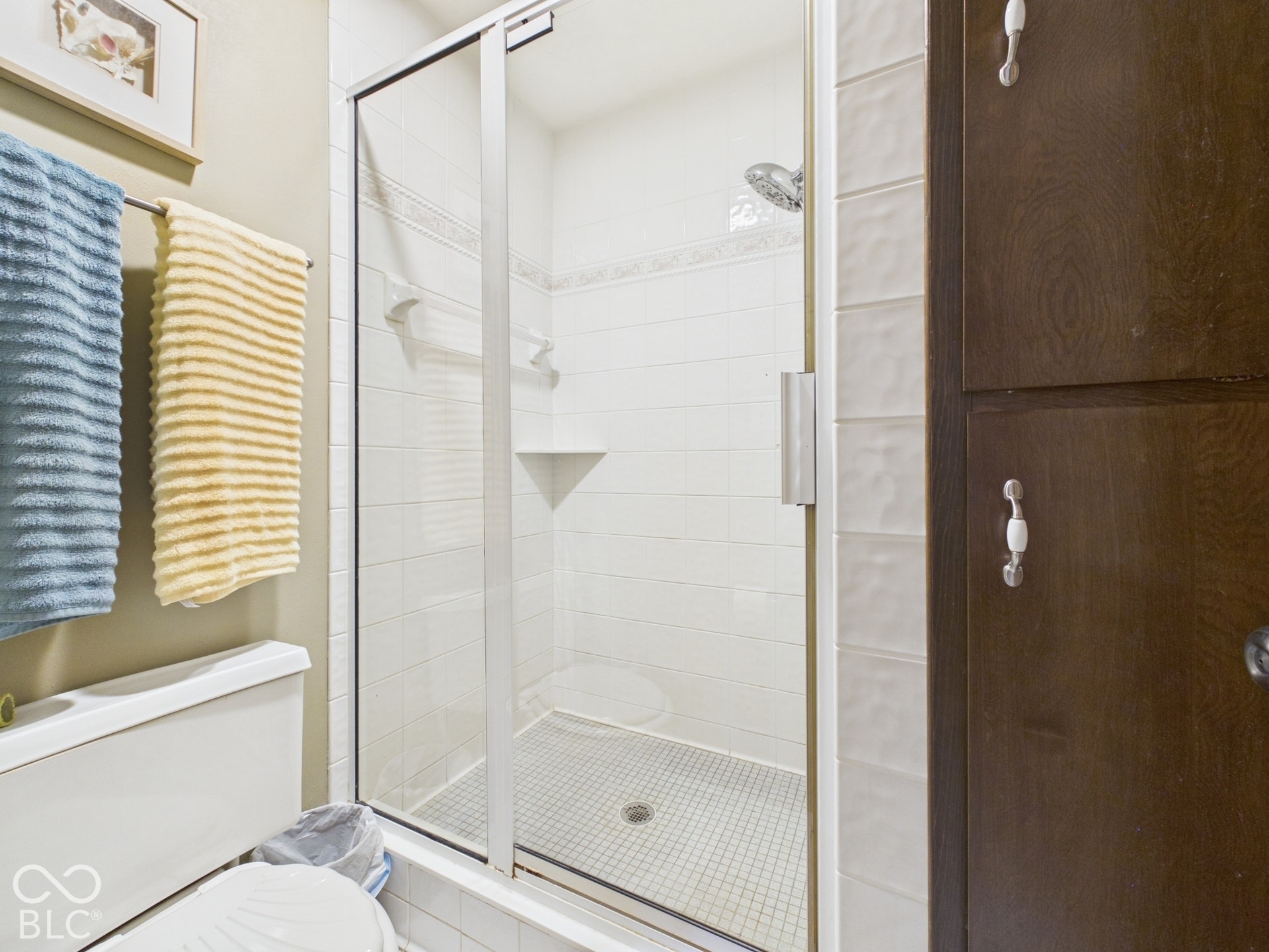 Glass-enclosed shower with white subway tile surround, integrated shower niche, and mosaic tile flooring