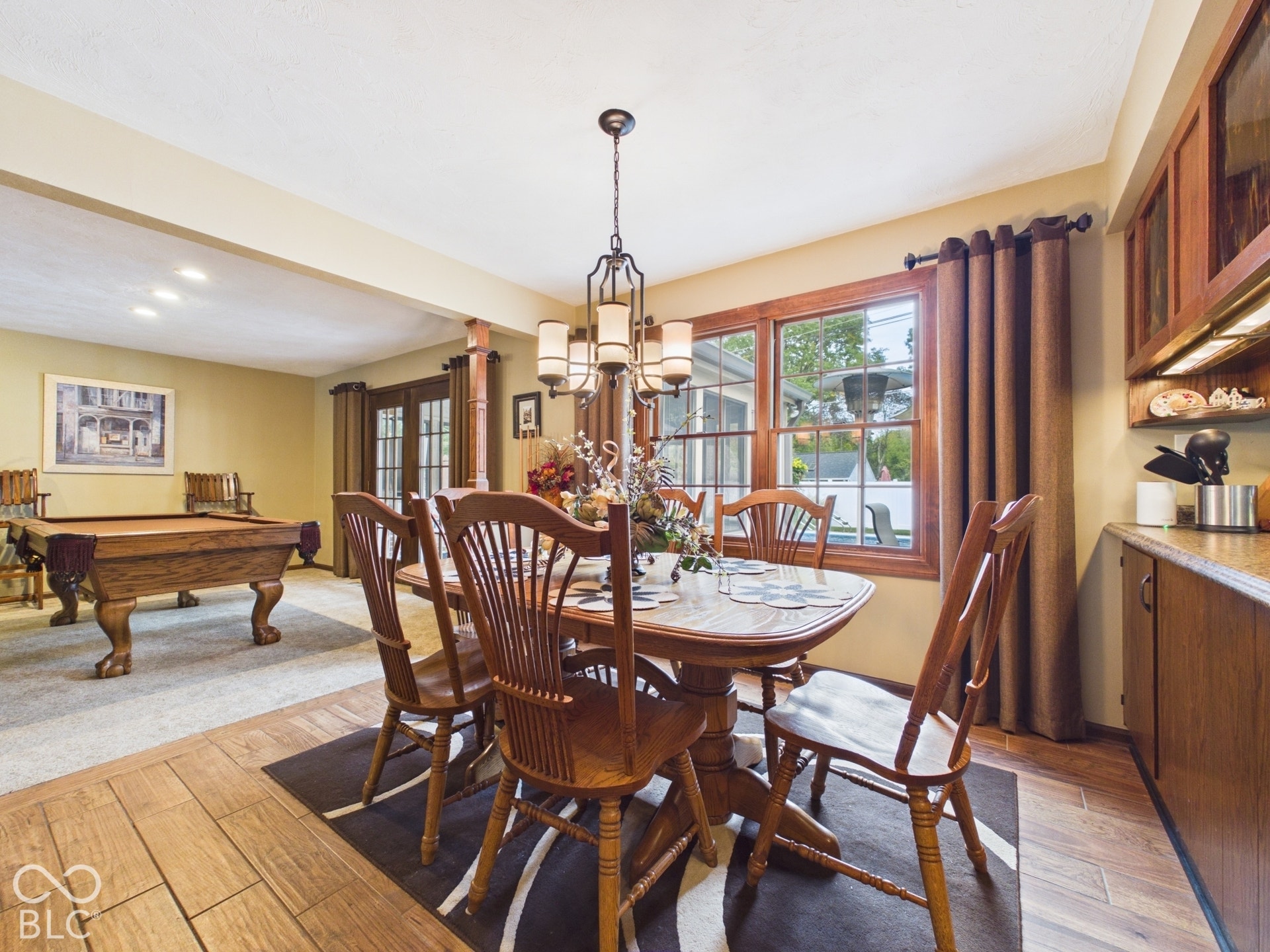 Wood-finish flooring, wood cabinetry with glass-front uppers, and a window with wood trim