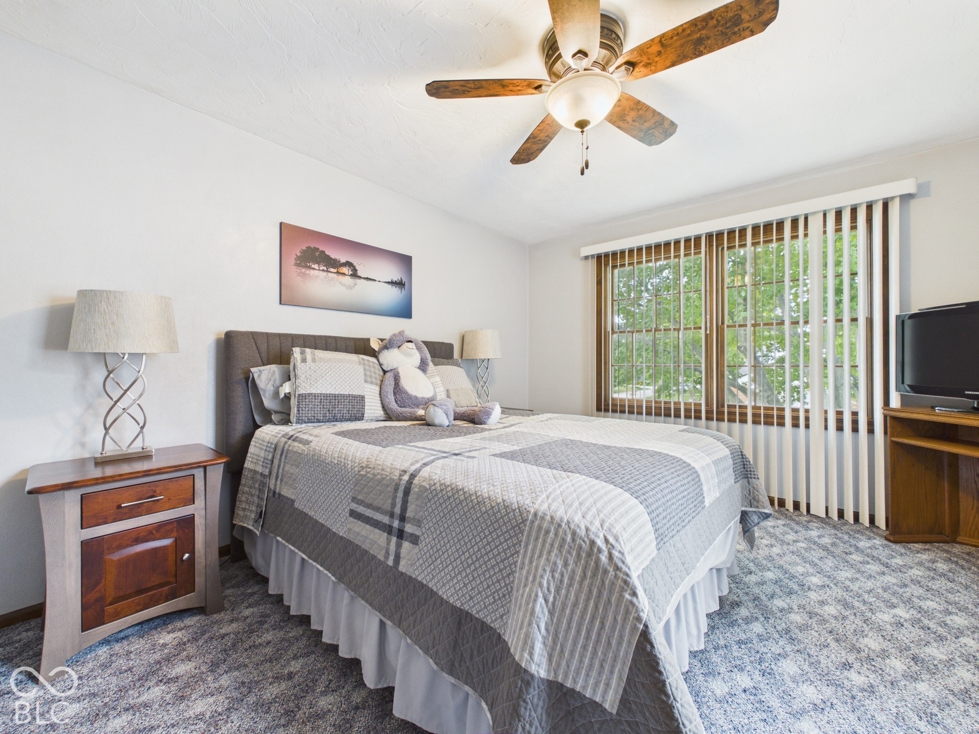 Textured carpeting, wood-finish window frames, and a ceiling fan with integrated lighting