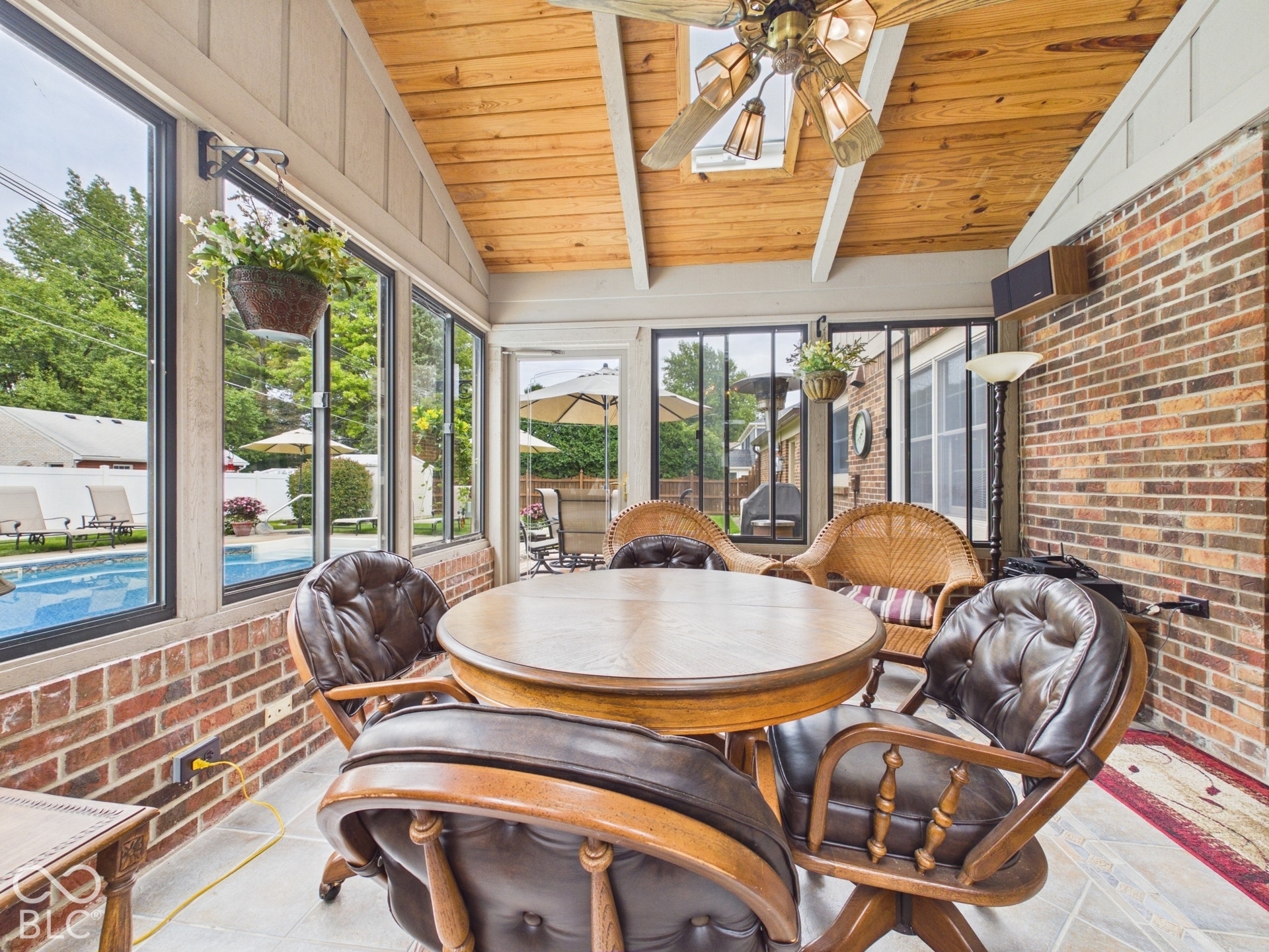 Sunroom featuring a vaulted wood-paneled ceiling, exposed brick wall, floor-to-ceiling windows, and tile flooring