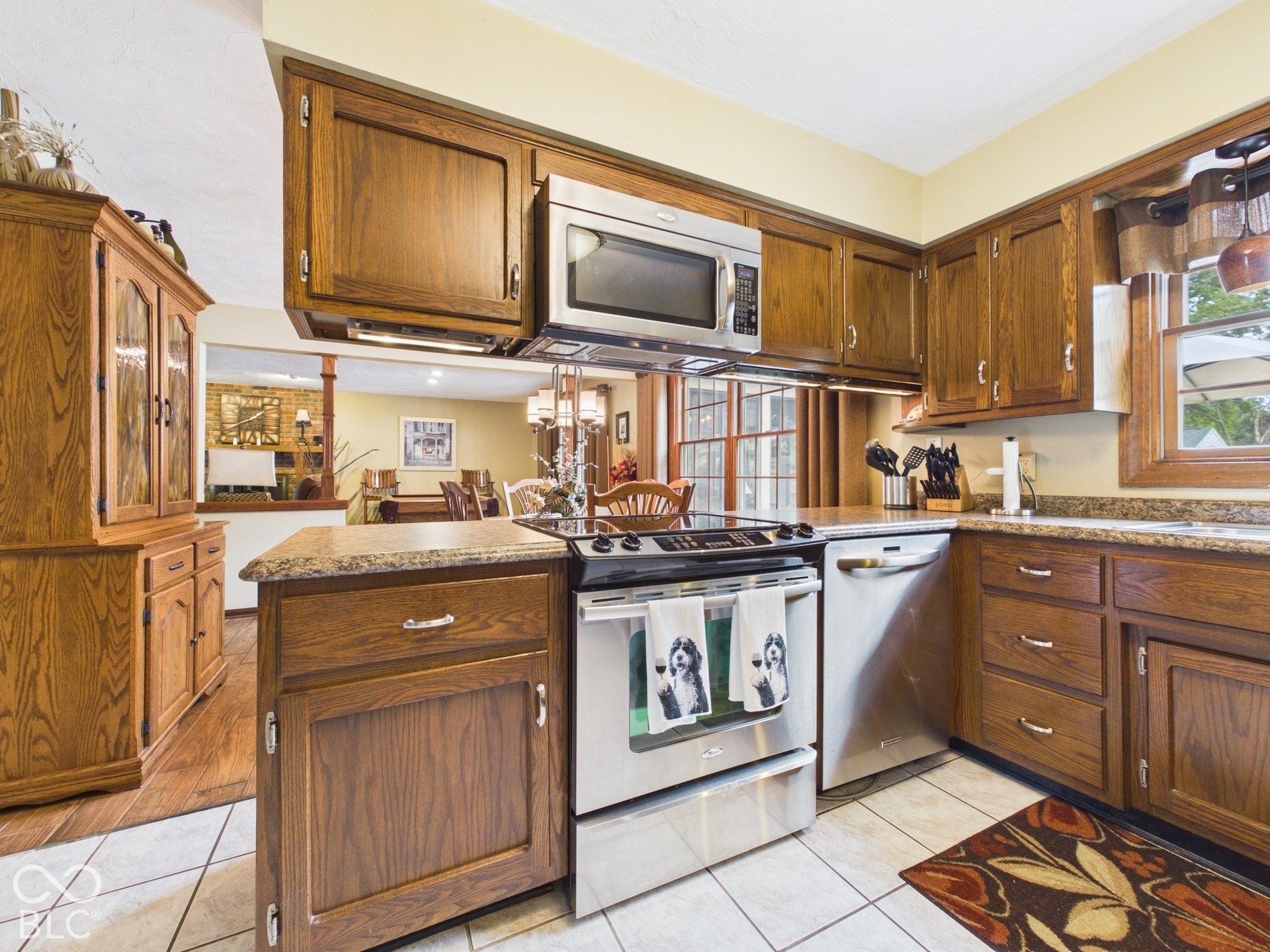 Kitchen featuring wood cabinetry, stainless steel appliances, granite-look countertops, and tile flooring