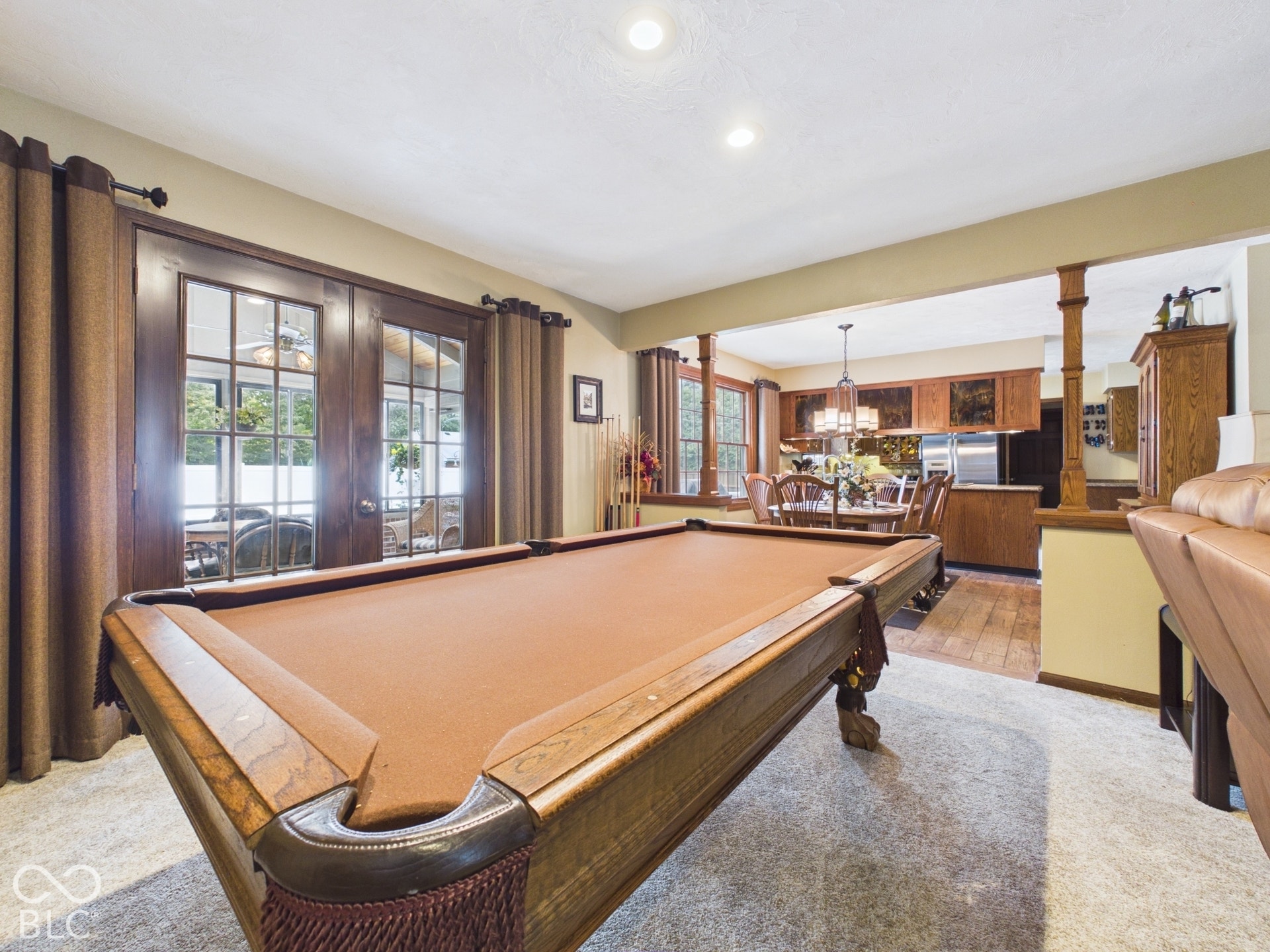 Hardwood French doors, recessed ceiling lighting, light-colored carpeting, an open archway, and wood-finish flooring in the adjacent area