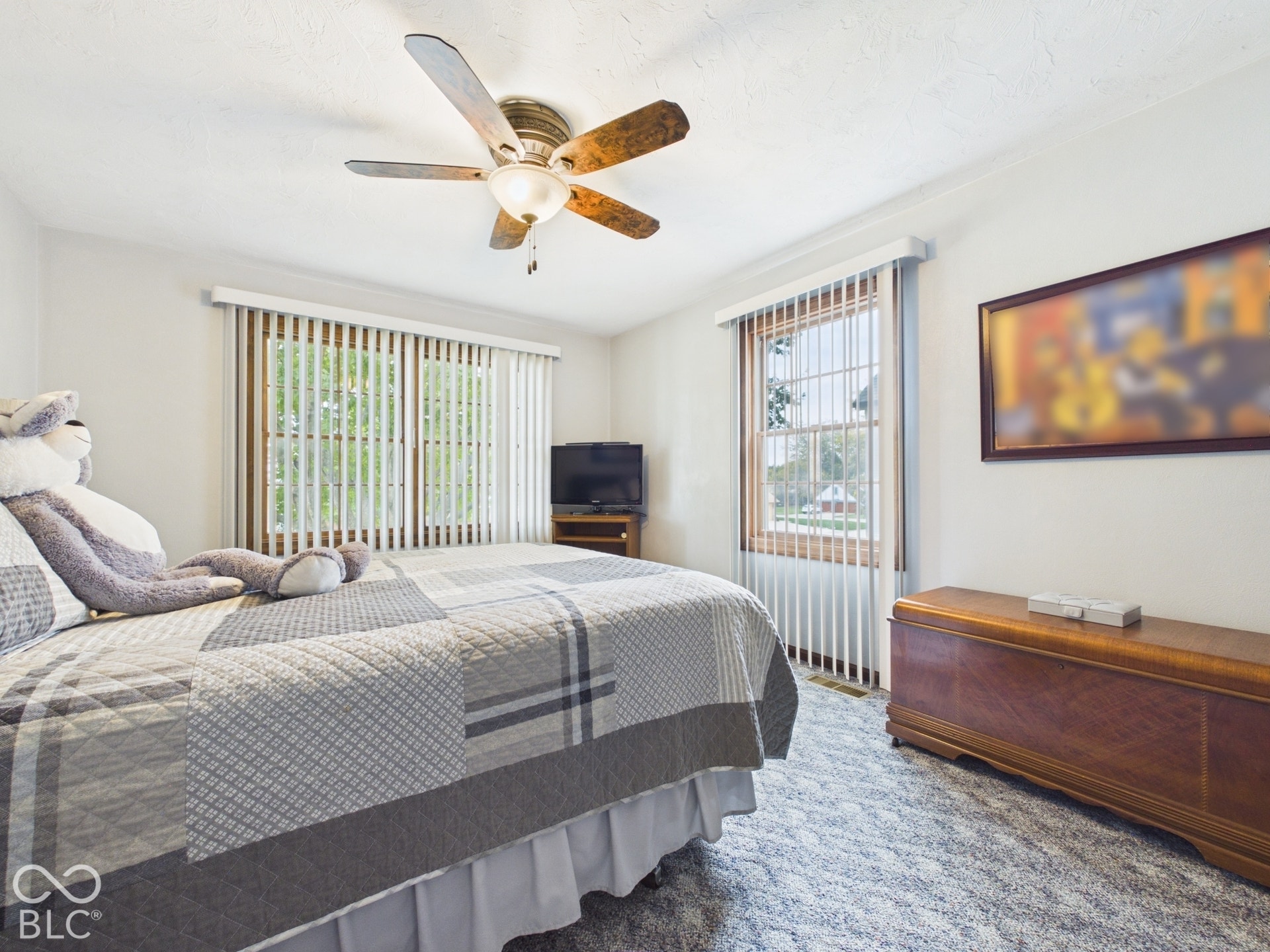 Ceiling fan with integrated lighting, wood-framed windows, vertical blinds, and textured wall-to-wall carpeting