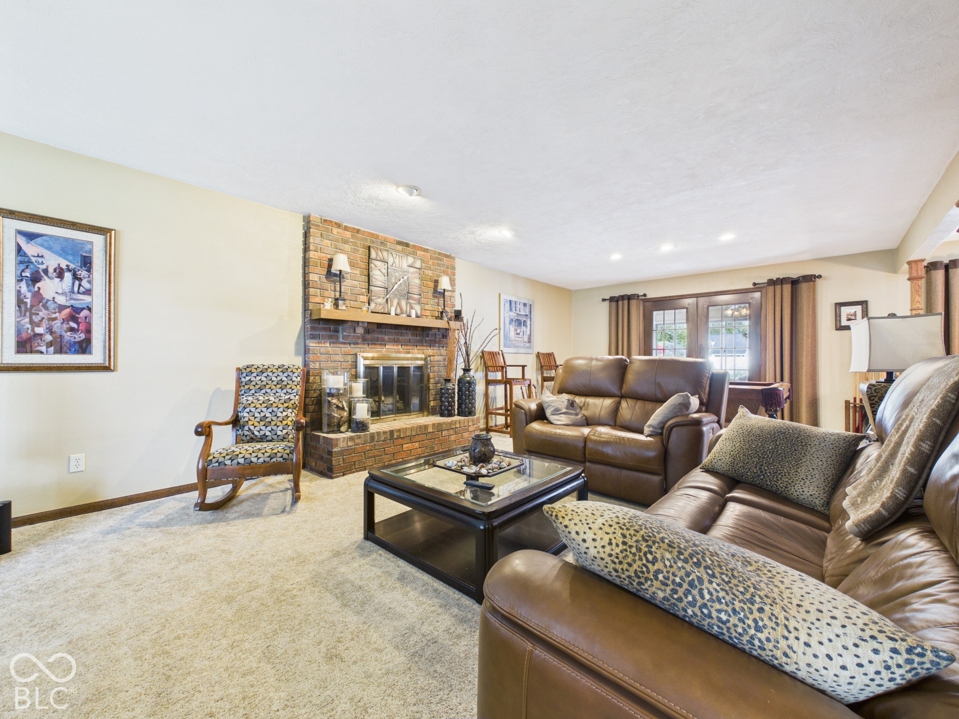 Brick fireplace with a wood mantle, recessed lighting, and french doors