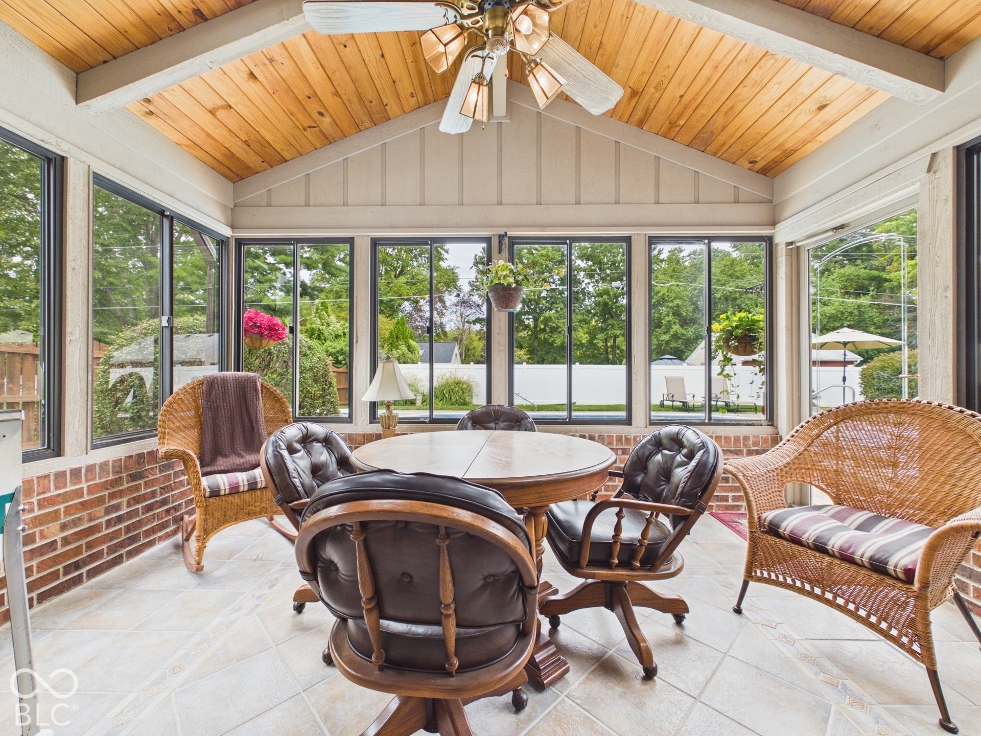 Sunroom featuring a vaulted wood-finish ceiling, exposed beams, full-height windows, brick-finish wainscoting, and tile flooring