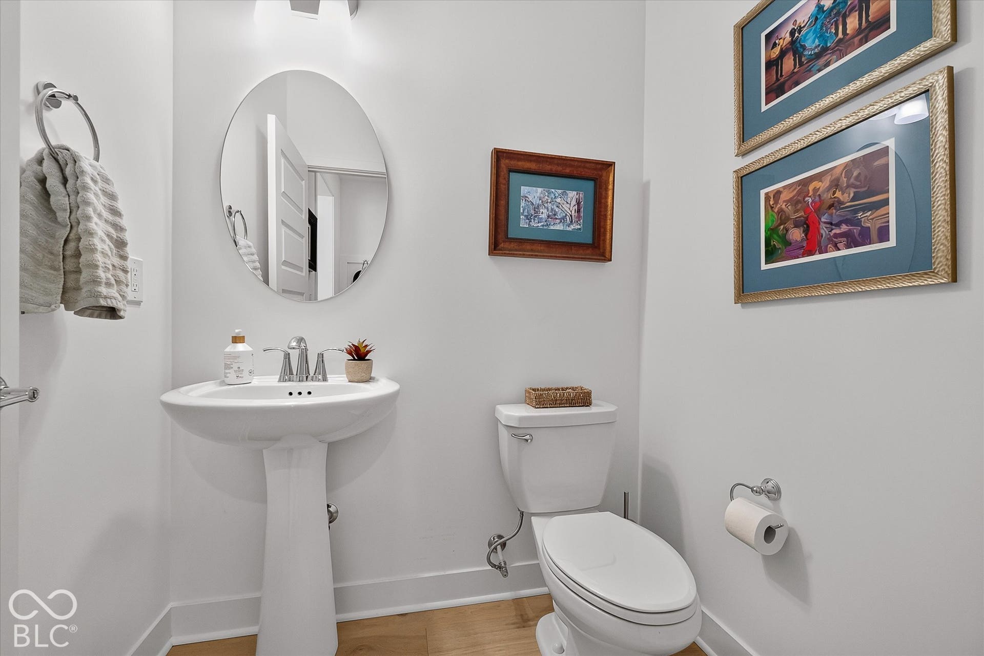 1405 Lake Haven Lane, Westfield, IN 46074 White pedestal sink with chrome faucet, oval wall mirror, and light wood-finish flooring