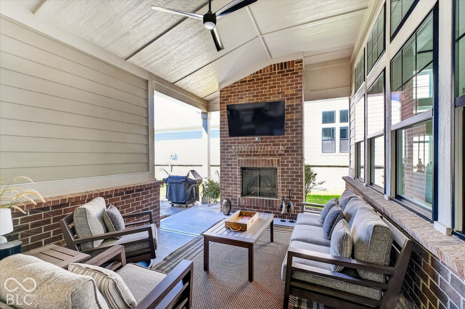 1405 Lake Haven Lane, Westfield, IN 46074 Expansive covered patio featuring a brick fireplace, a ceiling fan, a vaulted ceiling, and large windows