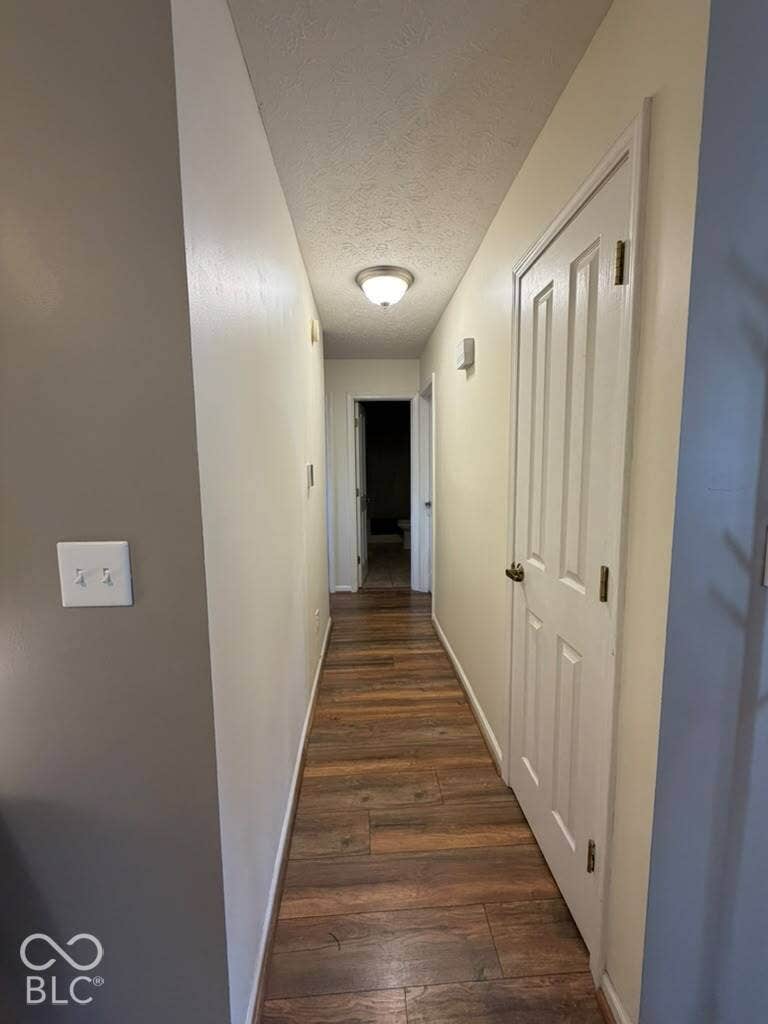 Hallway featuring wood-finish flooring, white paneled doors, and ceiling-mounted lighting