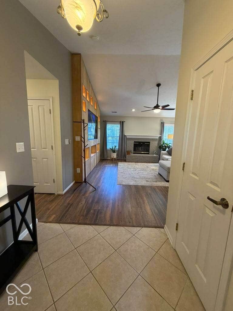 Vaulted ceiling with a ceiling fan and recessed lighting, wood-finish flooring, and a fireplace with a mantel