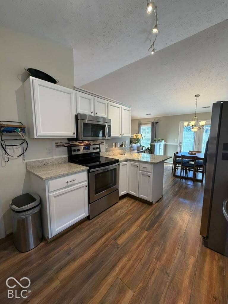 Kitchen featuring white cabinetry, stainless steel appliances, granite countertops, and wood-finish flooring