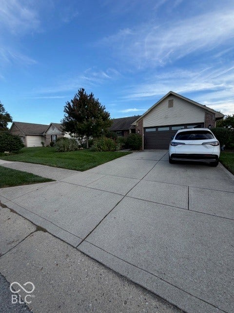 Concrete driveway, attached garage, brick facade, gabled roofline, front landscaping