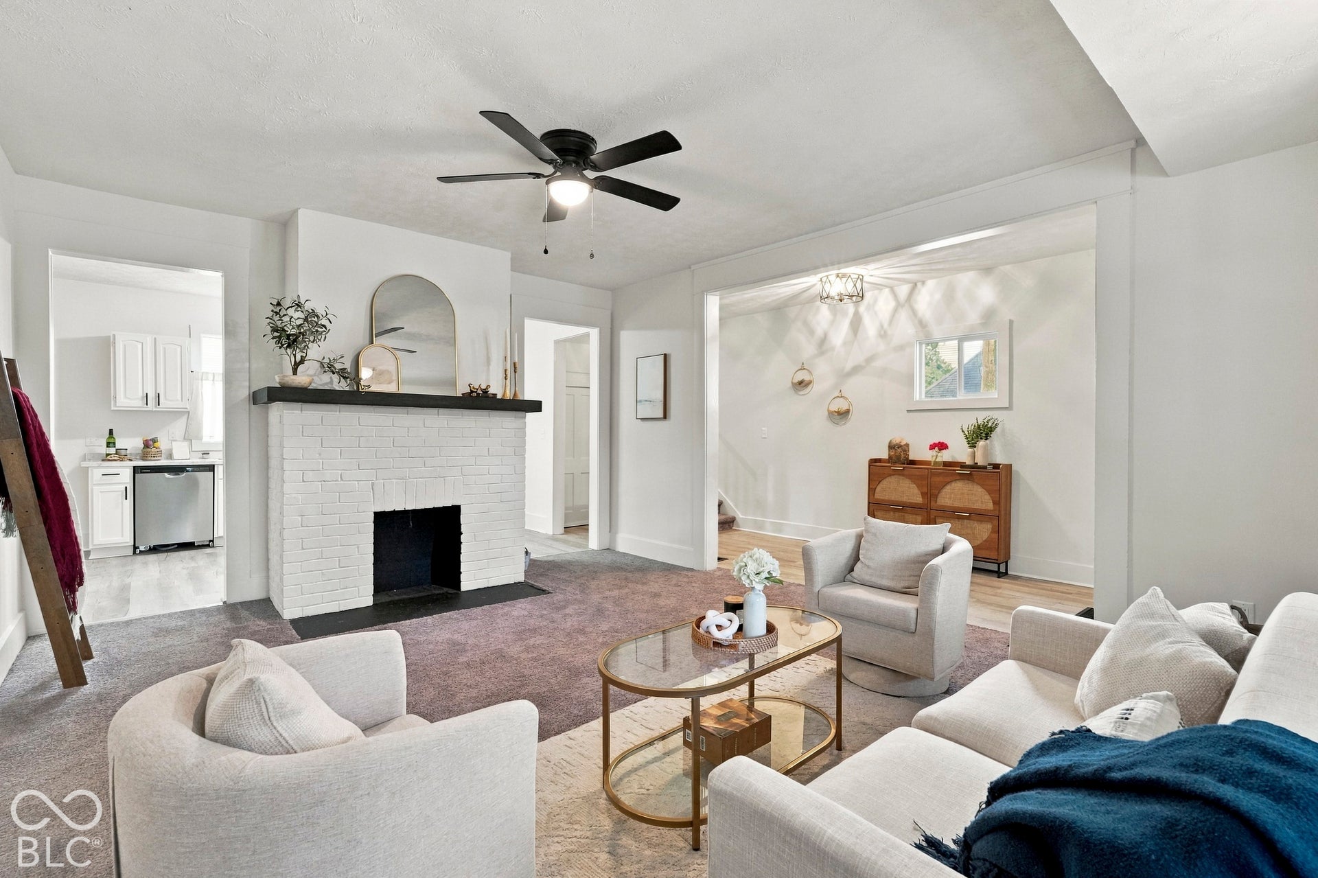 White painted brick fireplace with a dark wood mantel, matte black ceiling fan, and crisp neutral wall finish