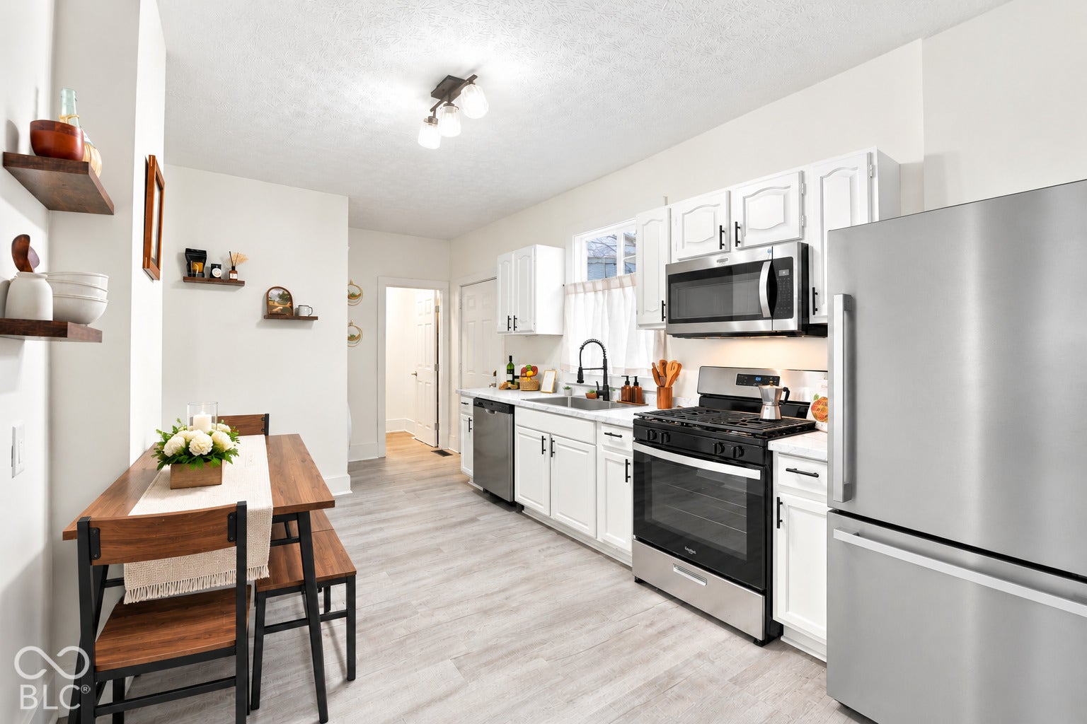 Kitchen featuring white cabinetry, stainless steel appliances, wood-finish flooring, a matte black kitchen faucet, and built-in wall shelving
