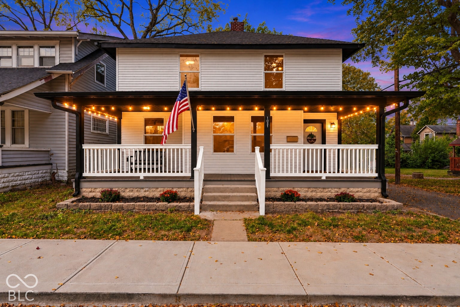 Virtually Altered - Two-story exterior featuring white horizontal siding, a covered front porch with white railing, and a stone foundation base