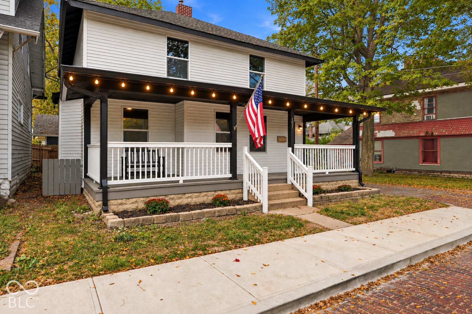 Two-story exterior featuring white horizontal siding, a full-width covered front porch with white railing, and a masonry foundation