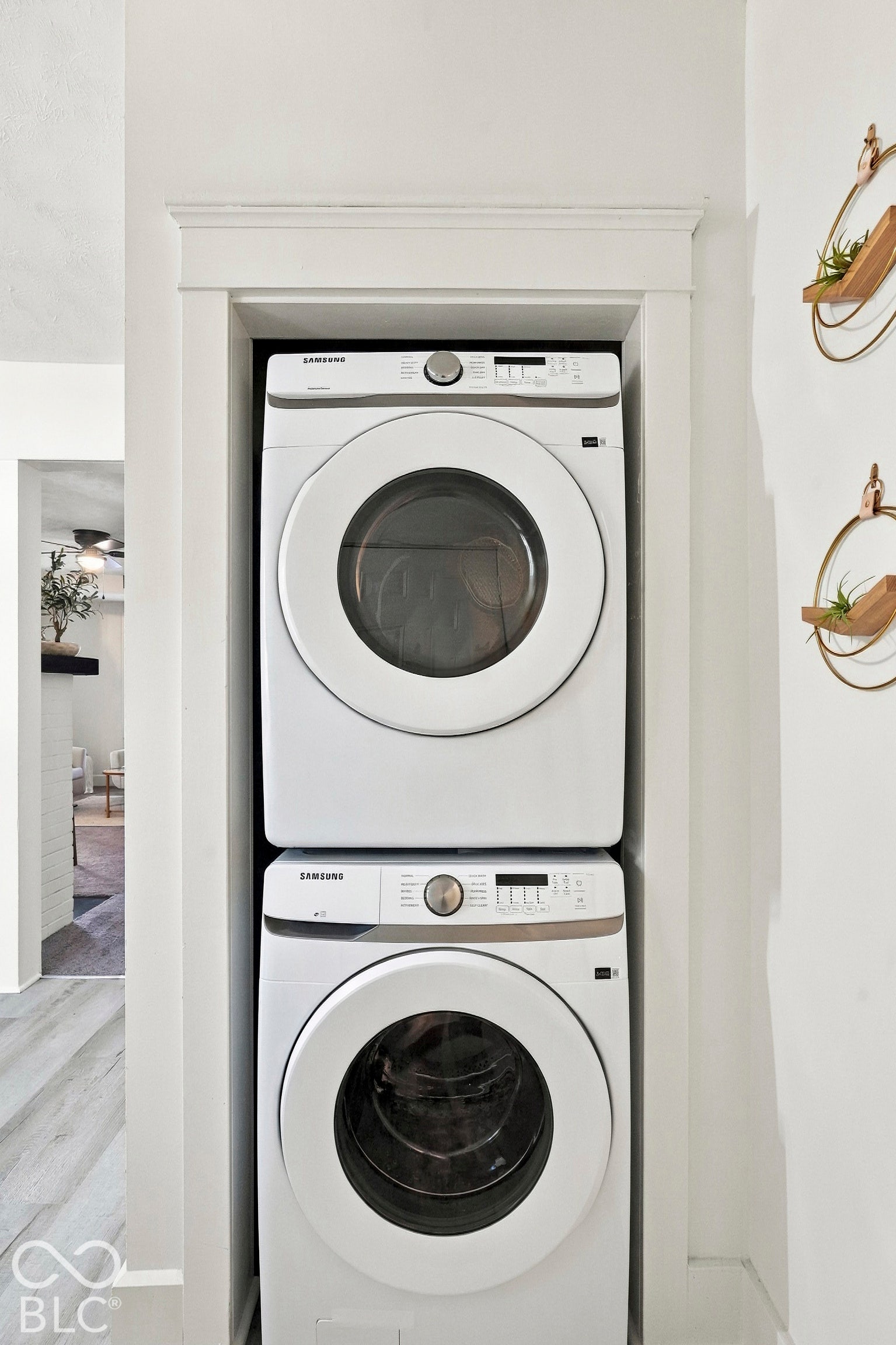 Main level stacked laundry center featuring white front-load appliances housed within a custom recessed alcove with traditional wood casing.